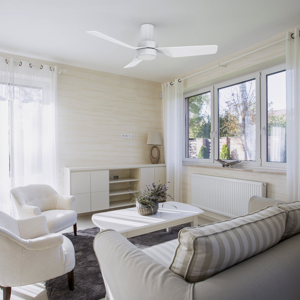A modern and minimalist living room featuring the Barnet 44-inch flush mount smart ceiling fan in a sleek white finish. The fan has three blades and an integrated LED light, providing both illumination and air circulation. Controlled via remote, it seamlessly blends with the bright and airy decor of the space. 