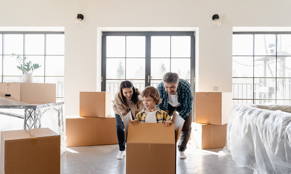 Happy family with one child having fun in their new home surrounded by boxes.