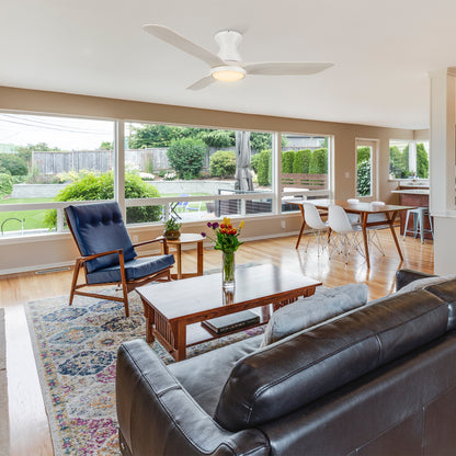 Lainey 52-inch low profile remote ceiling fan with light, installed in a spacious living room with large windows. 