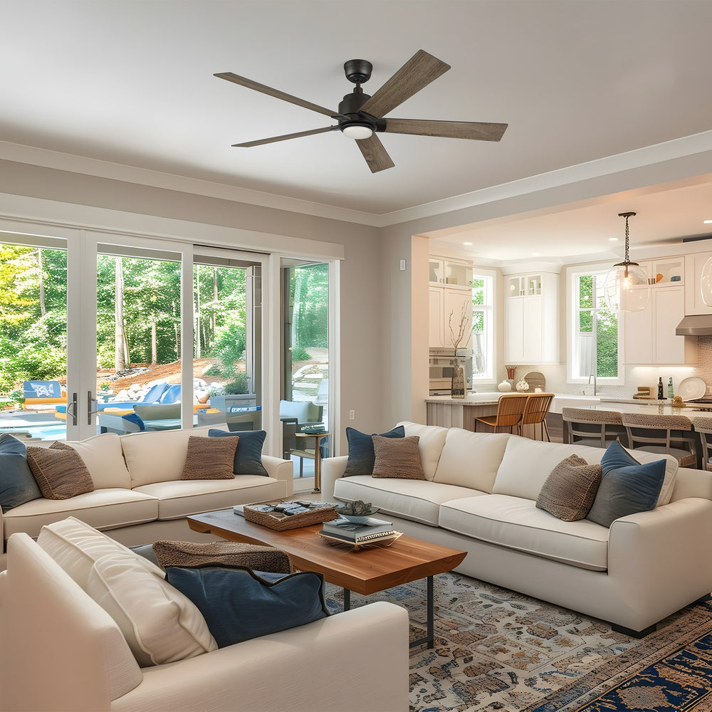 Kalmar 60-inch large ceiling fan with light installed in a modern open-concept living room with white sofas, wooden coffee table, and view of the outdoor patio through large glass doors. 